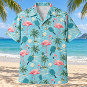 Front view of Coastal Flamingo Rally Pickleball Hawaiian Shirt with original elegant flamingo silhouettes standing beside generic pickleball paddles and perforated balls, small beach palms and simple court corners